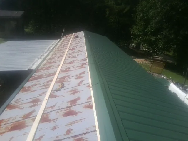 Old rusted panels beside newly installed green metal roofing — Wind Damage Roof Repair by Roofing Brothers in Imnaha