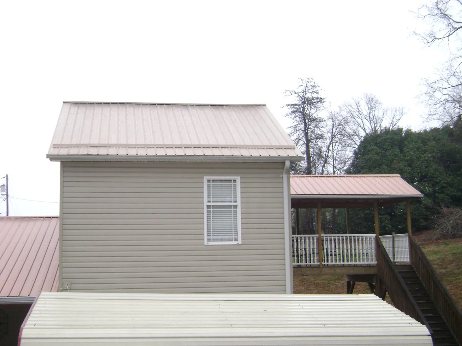 Tan metal roofs on a two story addition and attached porch, from a Roof Replacement job in Imnaha
